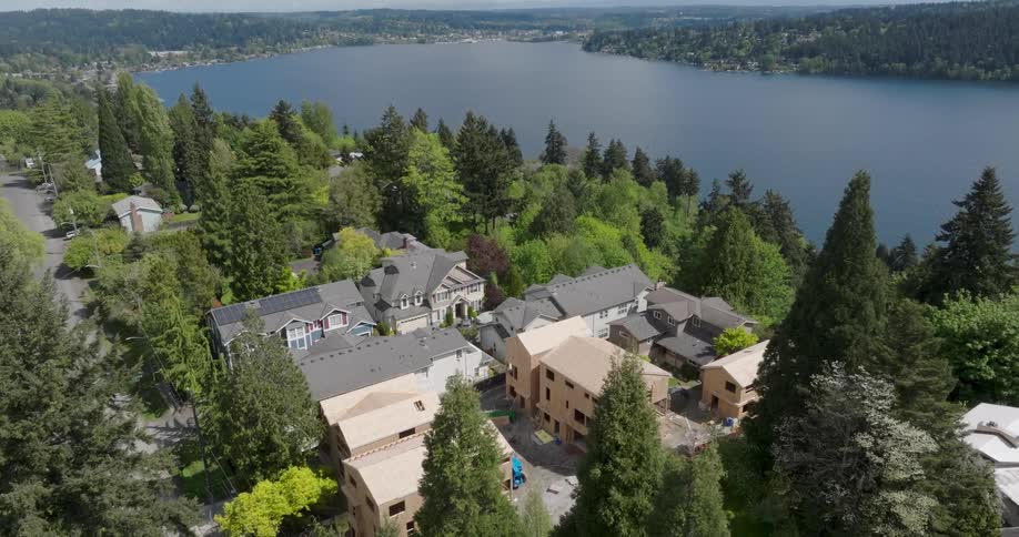 New townhomes under construction on a hillside neighborhood near the edge of a lake