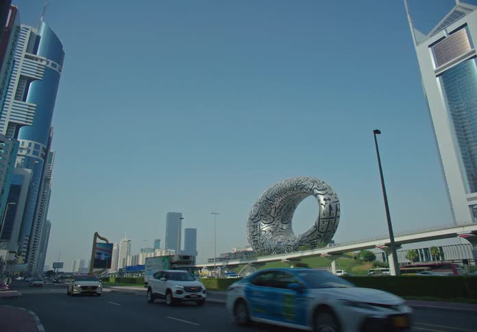 A busy street in dubai with the iconic museum of the future standing out amidst tall skyscrapers and bustling traffic