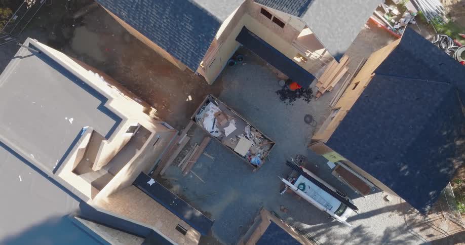 Construction debris fills a dumpster at a residential construction site