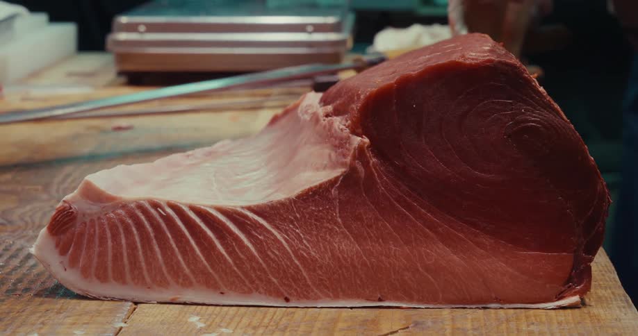 Large piece of fresh tuna on top of a wooden counter