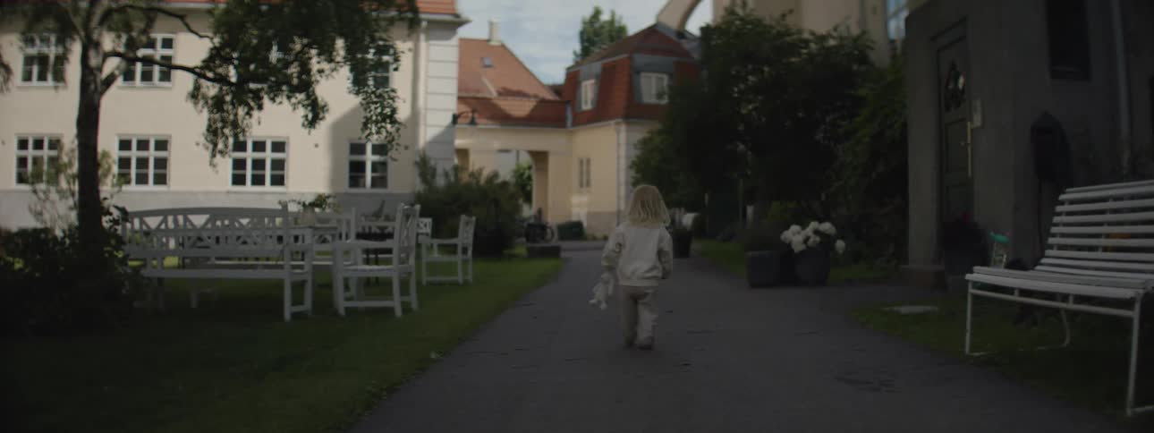 Small blonde child walking on a sidewalk in a residential neighborhood