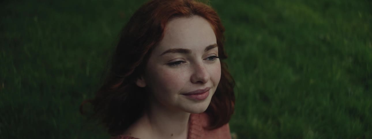 Woman sitting on grass with happy facial expression