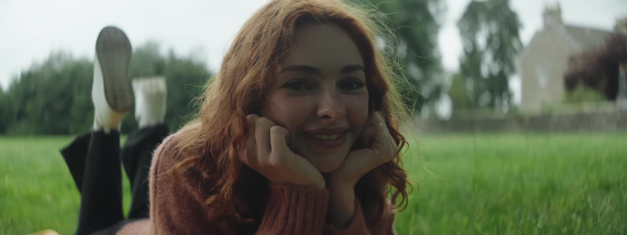Young woman lying on her stomach in the grass smiling