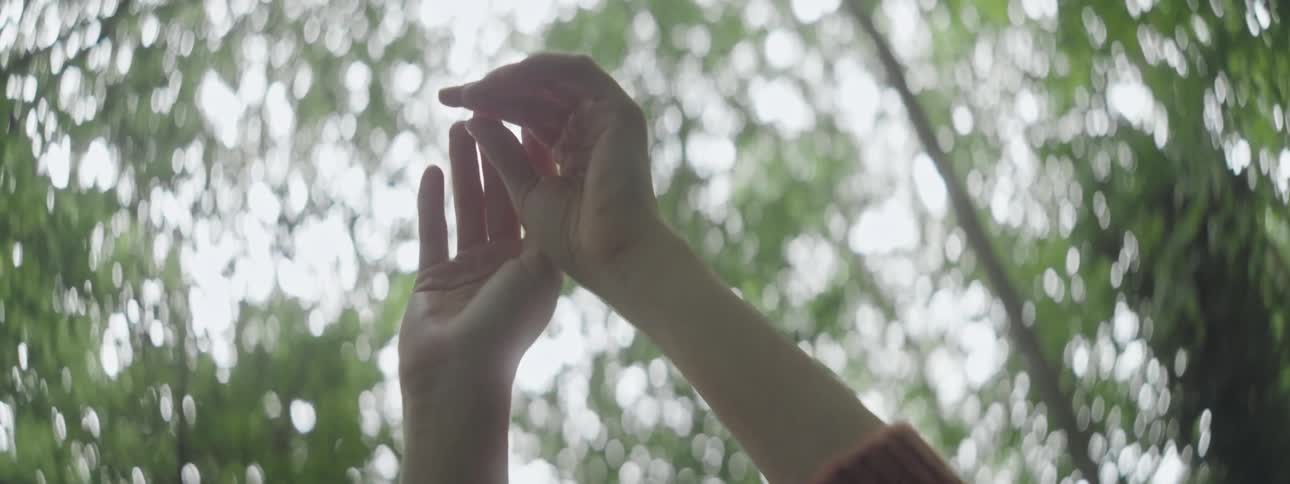Redhead woman with her arms up in a room surrounded by trees