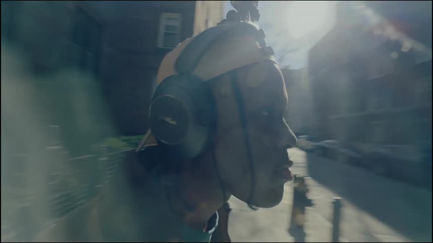 A close up clip of a black teenager putting on an earpiece