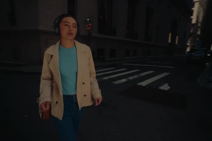 Woman with headphones walking down the street of a metropolis enjoying the music and dancing