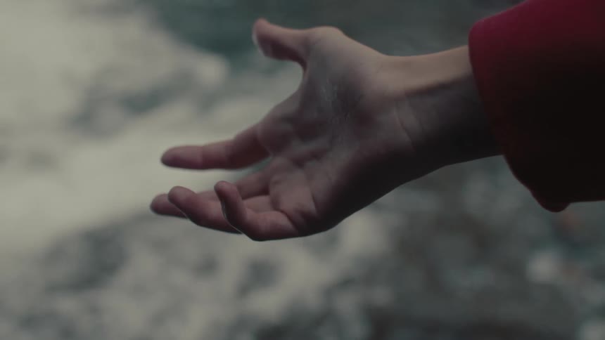 Closeup of a persons hand against a background of a river