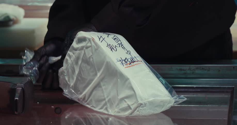 Hand with gloves closing the package of a piece of Tuna for Sashimi