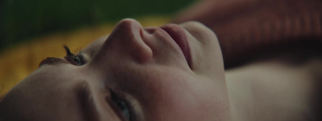 Closeup of a beautiful young woman resting on a blanket in a park looking up