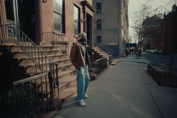 A man walks down the stairs of an apartment building and looks at his cellphone