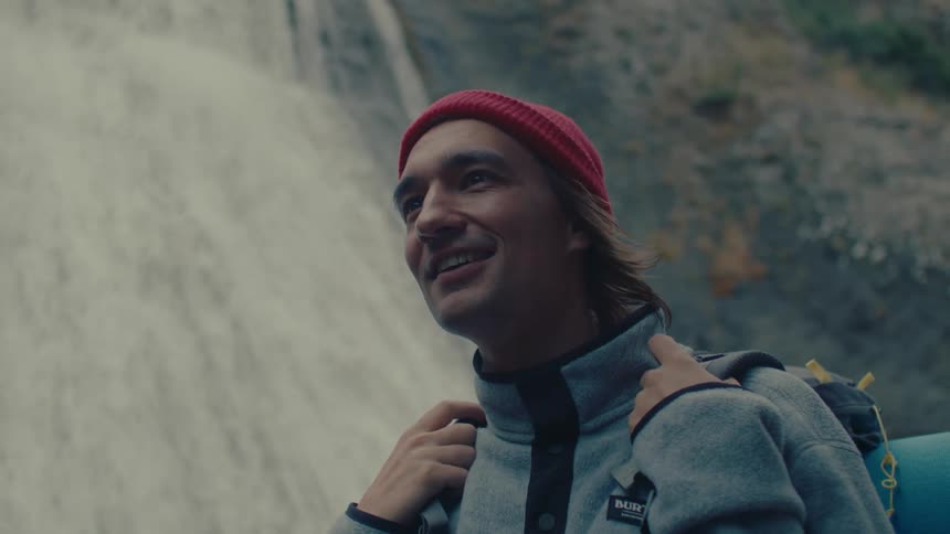 A medium clip of an hiker standing in front of a waterfall