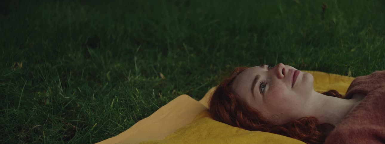 Side portrait of a redhaired woman lying on the grass
