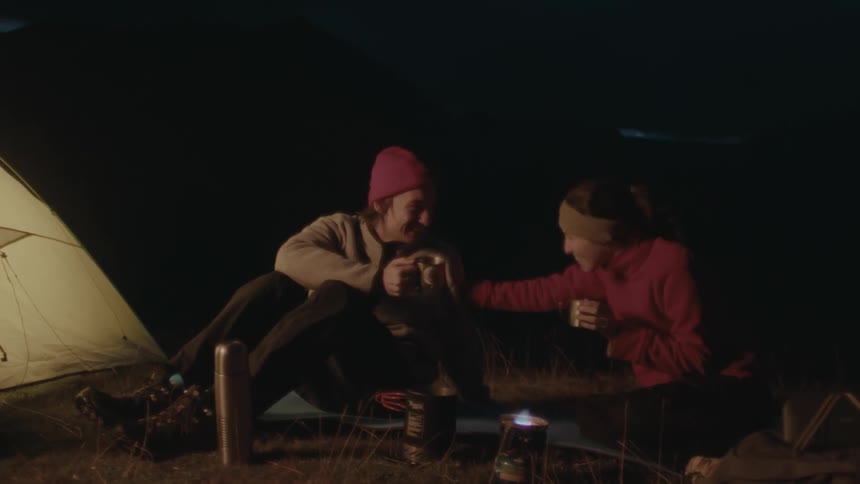 A clip of a lady and a man outside the tent having a drink