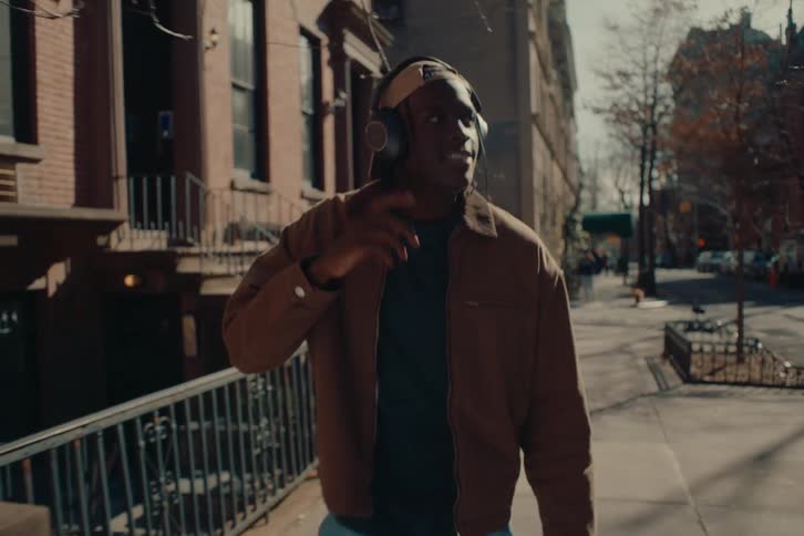 Man with headphones walking on a city sidewalk