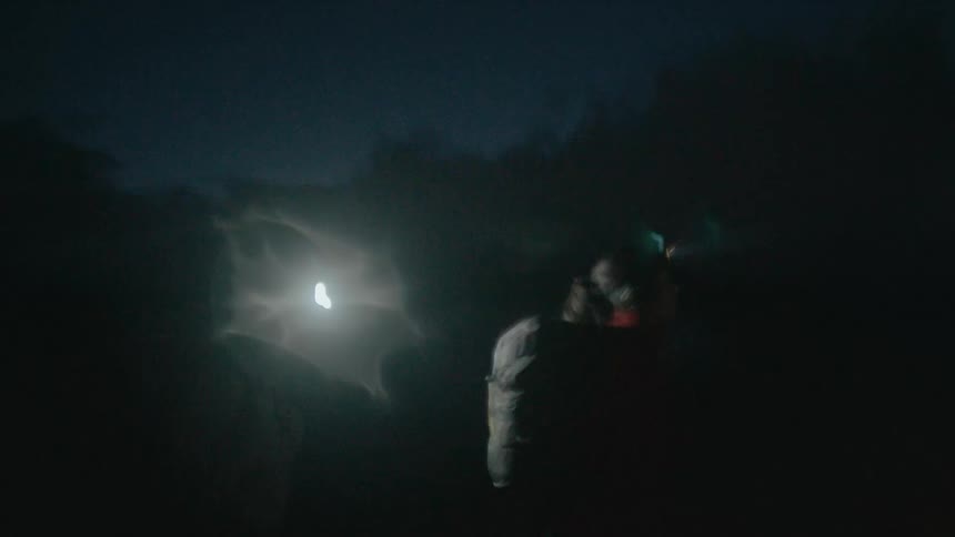 Two people with headlamps walking in a natural environment at night