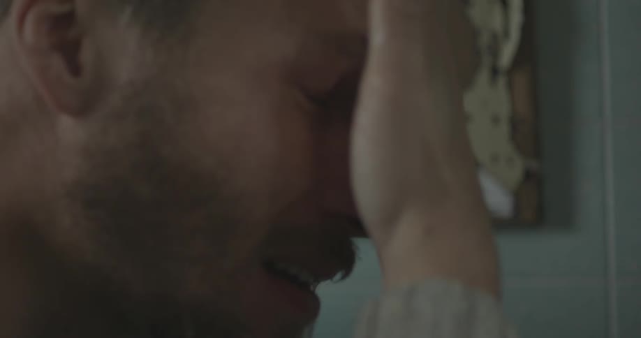 Man wipes his face with water in a room