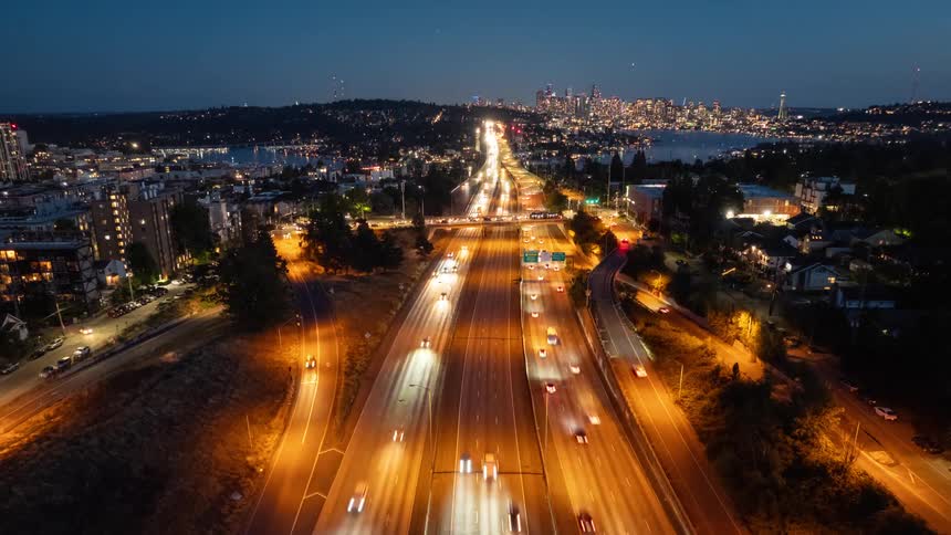 Evening traffic flows along I-5 and the ship canal bridge with downtown Seattle sparkling in the distance