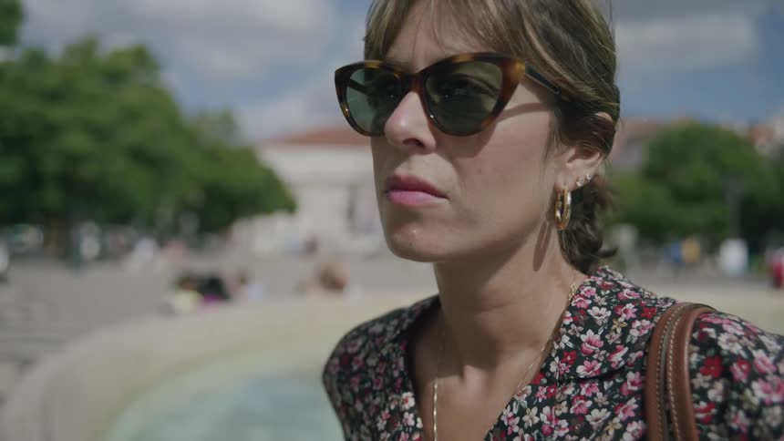 Woman in a public space putting on sunglasses