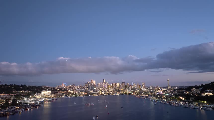 Tilt down reveal from an evening sky to many small sail boats zipping around Lake Union