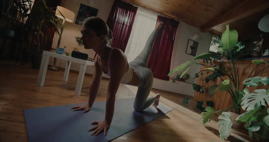 Woman on a fitness mat stretching her body indoors