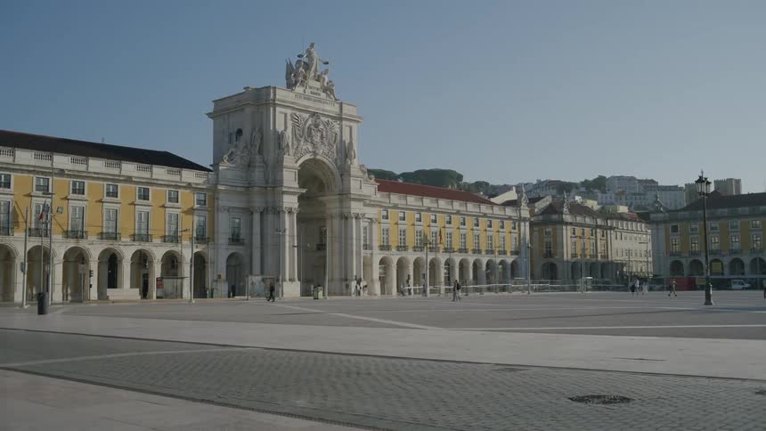 People walk around a square near a large ancient european building in a city