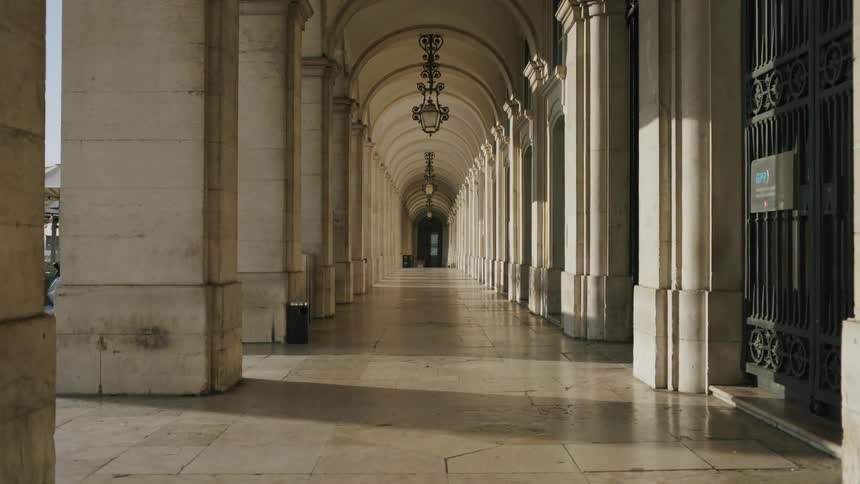 Sunlight passes between columns into a long external corridor with arches
