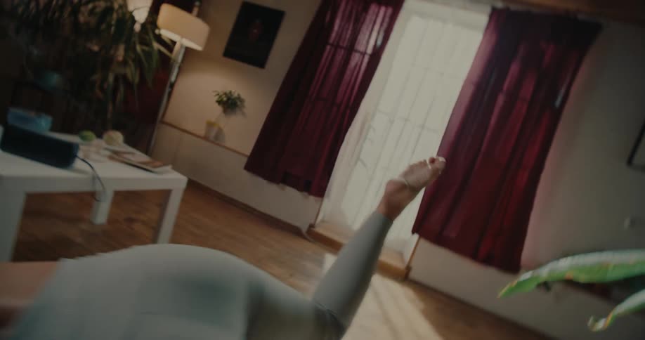 A woman stretching over a yoga mat in the living room