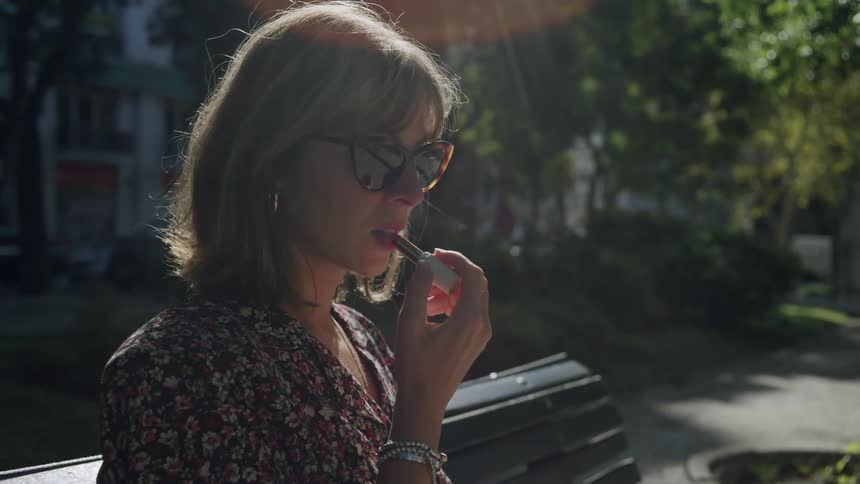 Woman sitting in a public space touching up her lipstick