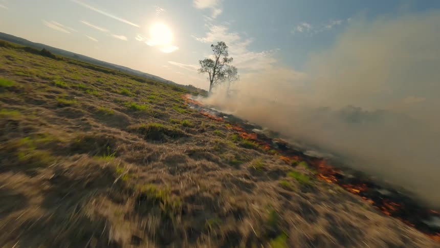 Fpv drone aerial view of a vast field on fire