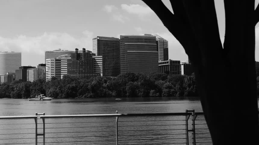 Black and white shot looking over a lake at a building