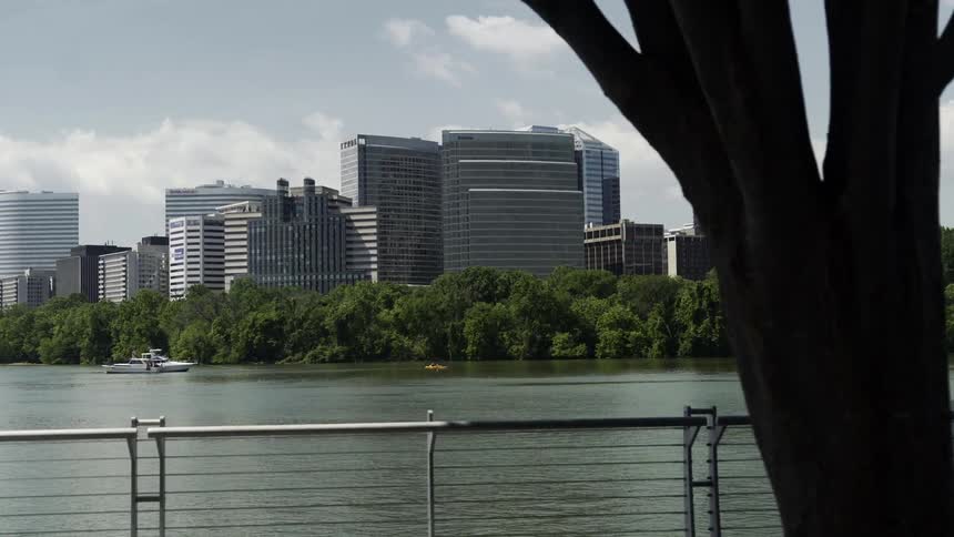 Landscape of modern buildings of a metropolis on the edge of trees and a canal