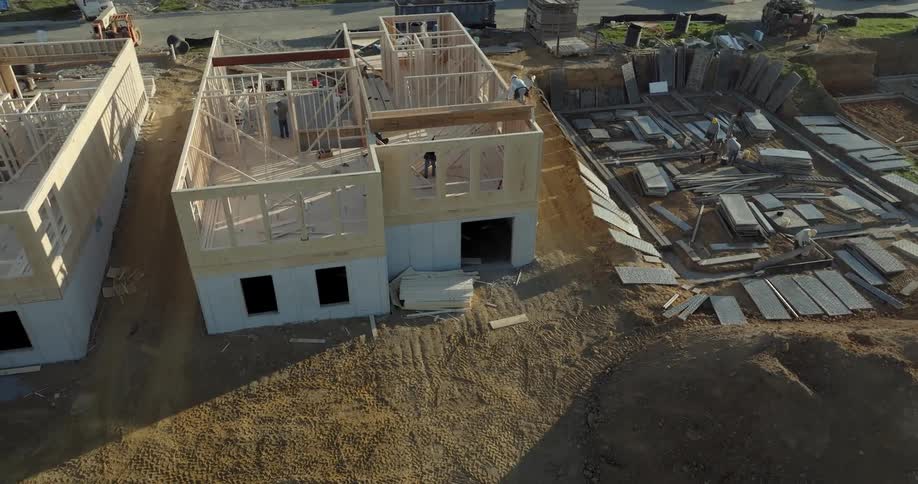A group of men work on building two houses next to each other