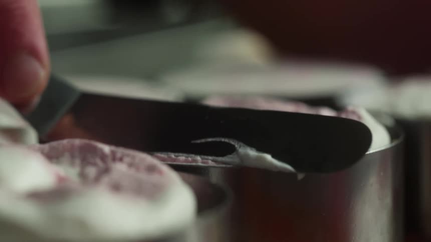 Close up of sweet pastries in mugs and a hand with a spatula arranging them
