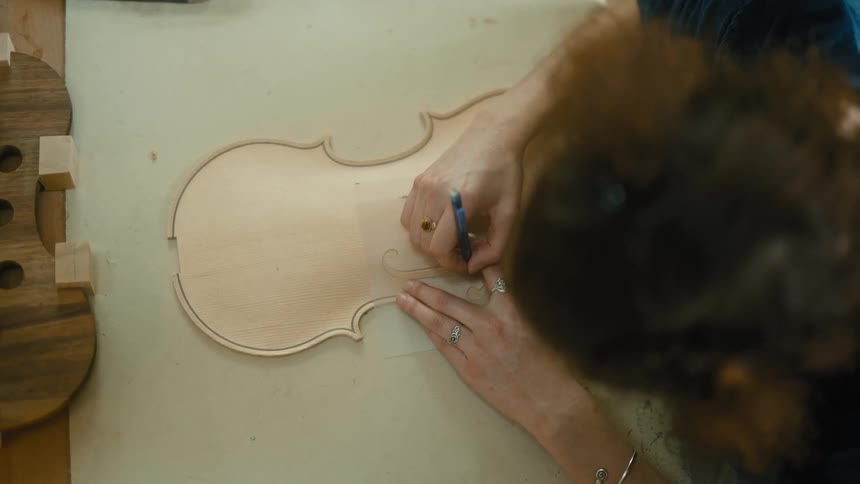 Top view of a woman with a pen drawing the shape of a violin