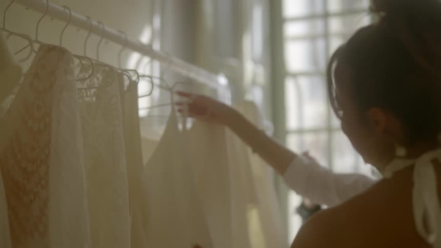 Two women looking at white dresses in a store