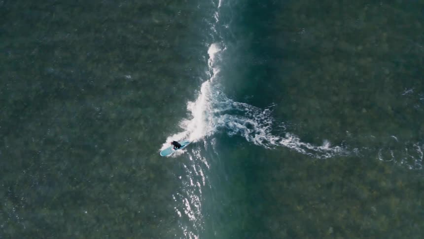 Aerial view of a person surfing a wave in the ocean