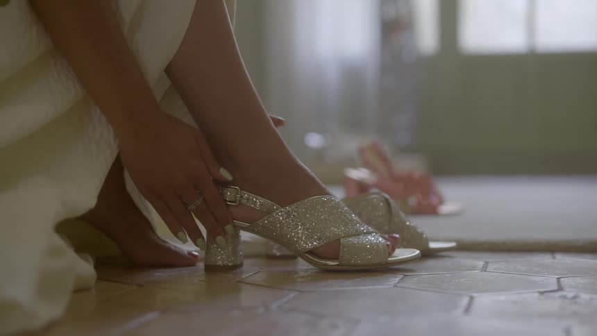 A woman sitting on the floor putting on a pair of highheeled sandals