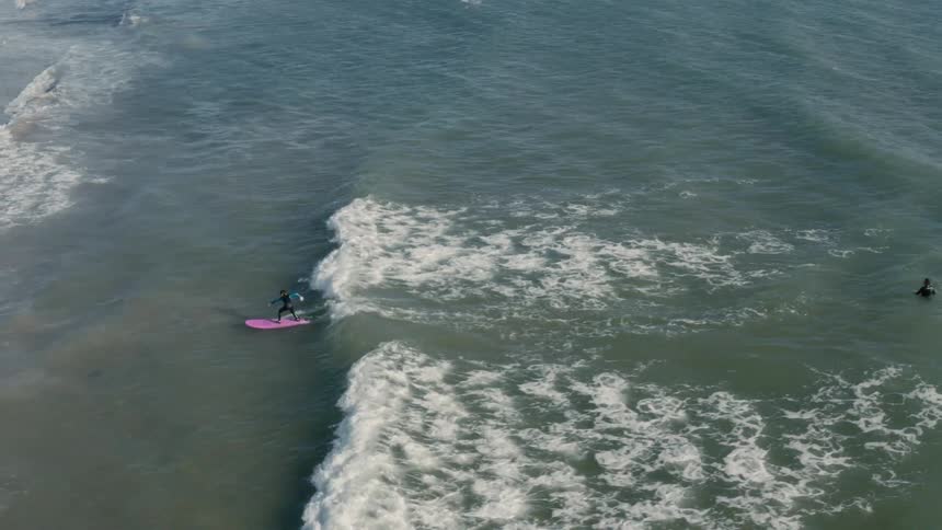 A surfer helps push another surfer to shore