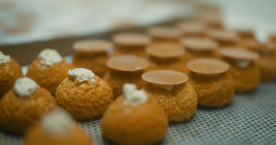 Baker places decorations on round creamfilled food