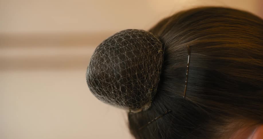 Female brunette wears a hair net over her hair bun