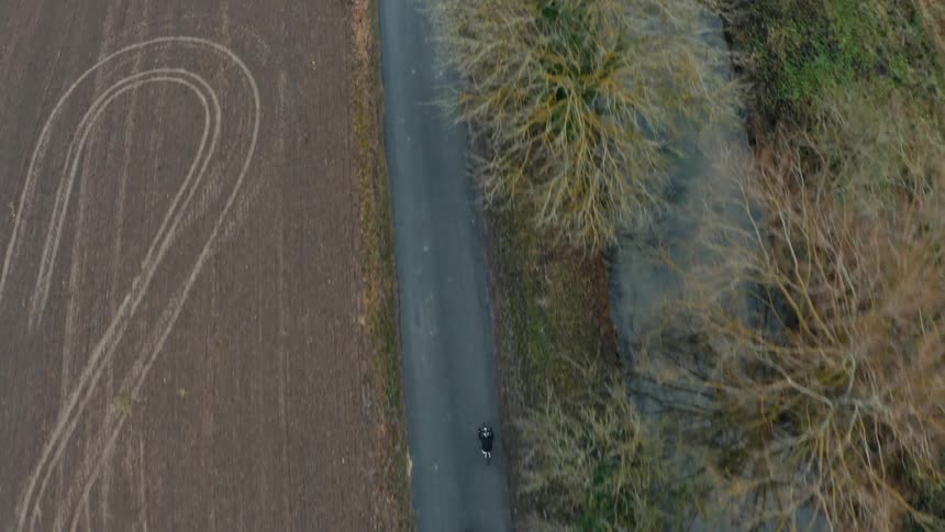 An aerial view of a country road with two cyclists riding along the road