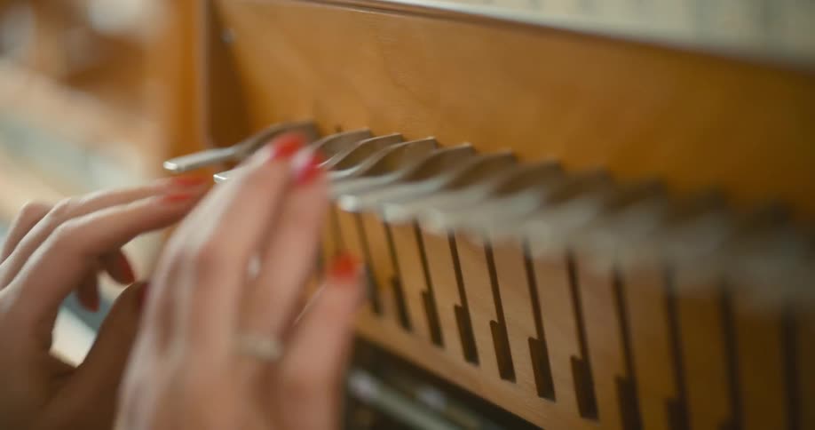 A closeup of hands with red nail polish adjusting the stops of a pipe organ