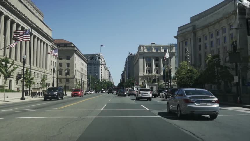 Traffic passes by government buildings on a sunny day
