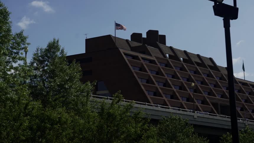 Building in the background next to a highway with flags on top