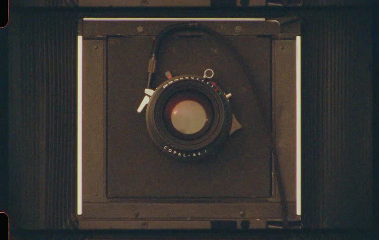 Closeup of a hand adjusting the lens of an old camera