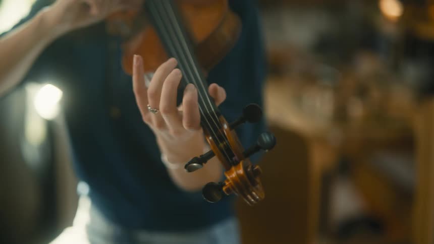 A woman tests out a violin in a manufacturing facility