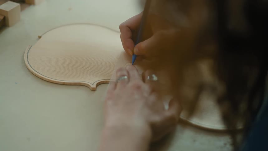 Woman carpenter with a pen shaping a violin
