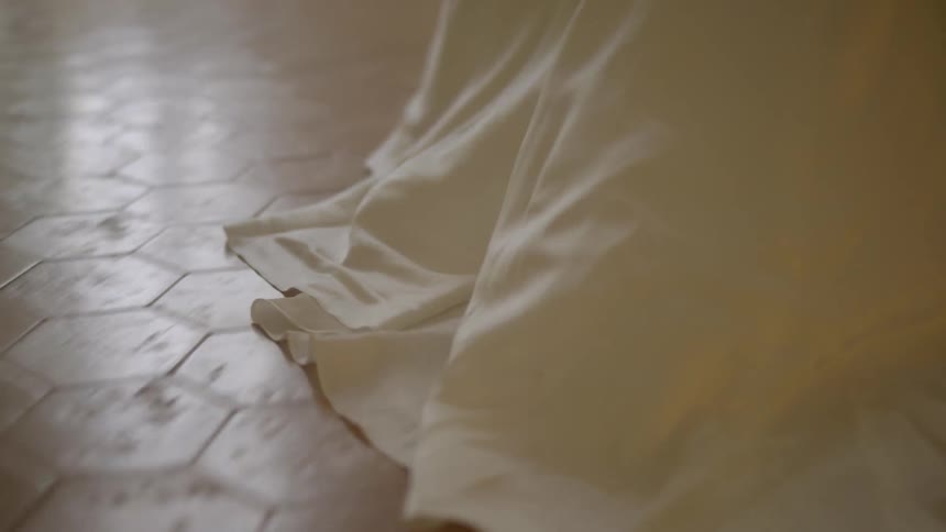 Closeup of the back of a white dress dragging on the floor