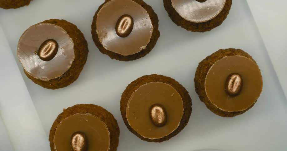Pieces of circular cake with a nut on the top sit on a white tray