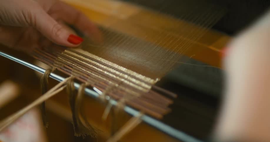 Hands of a woman using a retro fabric weaving machine
